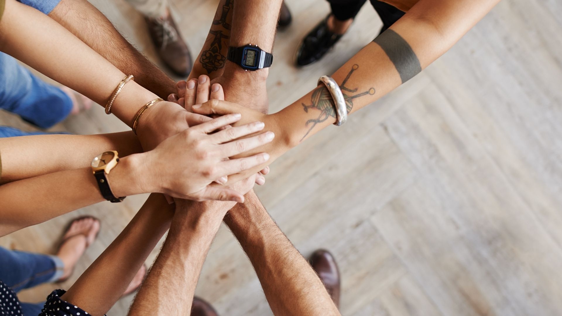 Hands of a diverse team joined together in the center, symbolizing collaboration and shared trust within an organization.